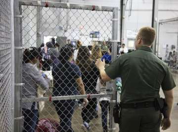 In this photo provided by US Customs and Border Protection, a US Border Patrol agent watches as people who’ve been taken into custody related to cases of illegal entry into the United States, stand in line at a facility in McAllen, Texas on Sunday.
?