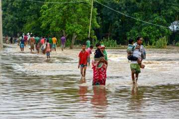 People shift to safer places from a flooded locality after heavy downpour, at Nam Doboka village in Hojai district of Assam.