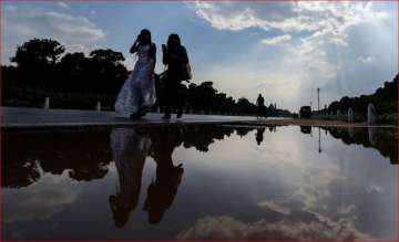 Women walk past a puddle of water at Rajpath in New Delhi after a short spell of rain.