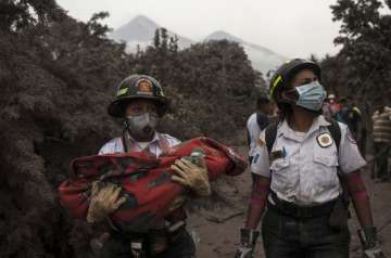 A firefighter carries the body of a child recovered near the Volcan de Fuego, which means in Spanish Volcano of Fire, in Escuintla, Guatemala, Monday, June 4, 2018. A fiery volcanic eruption in south-central Guatemala sent lava flowing into rural communities, killing dozens.