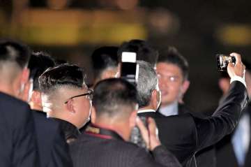 North Korean leader Kim Jong un, seen from back, takes a selfie with Singapore Foreign Minister Vivian Balakrishnan as they walk on the Jubilee Bridge as he tours Singapore on Monday.