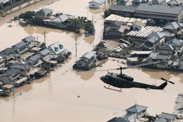 A helicopter flies over a flooded housing area in western Japan