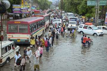 Pedestrians wade across a waterlogged road after monsoon rainfall, in Mathura.