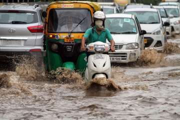 Commuters wade through water-logged road in Gurgaon as heavy rains continue to batter Delhi-NCR. (Photo/PTI)