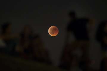 People watch from atop a hill a red moon during a complete lunar eclipse at the Tio Pio park in Madrid.?
?