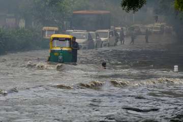 Vehicles wade across a waterlogged street after monsoon rain in New Delhi, on Monday.