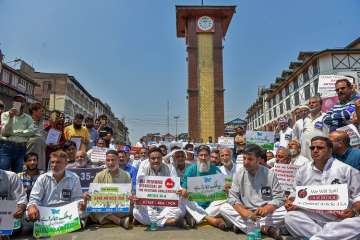  
 Kashmiri traders hold placards and raise slogans during a sit-in protest against the petitions in the Supreme court challenging the validity of Article 35A, in Srinagar on Sunday.
