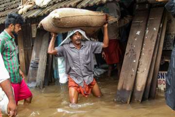 A person carries a grain sack as his house gets flooded after Kakkayam dam was opened following heavy monsoon rainfall, in Kozhikode