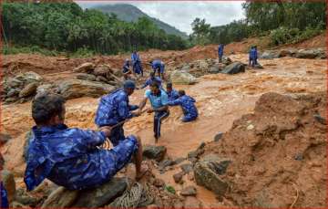 Rescue workers search for the bodies of missing persons after a landslide, triggered by heavy rains and floods, at Nenmara in Palakkad on Friday