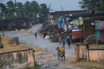 Ganjam: Locals walk near their houses as Cyclone 'Titli' hits the coast, in Ganjam, Thursday, Oct 11, 2018. 