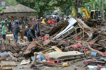 Residents inspect a house damaged by tsunami in Indonesia