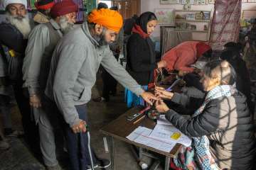 An election officer puts indelible ink mark on the finger of a voter at a polling station during Punjab Panchayat elections, on the outskirts of Amritsar.