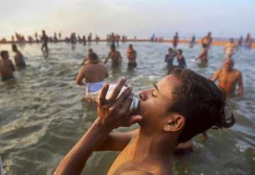 A devotee blows a conch shell after taking a holy dip at Sangam during Kumbh Mela