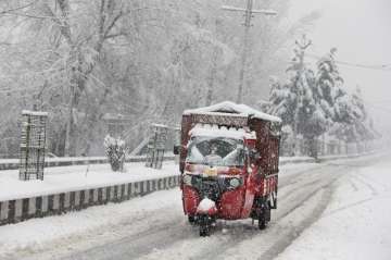 An auto-rickshaw drives on a snow-covered road on the outskirts of Srinagar on Thursday. 