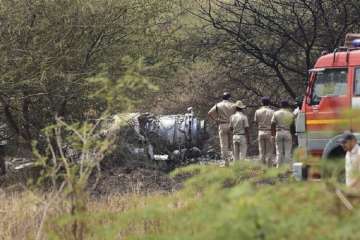 Police personnel stand near the wreckage of the Mirage-2000 fighter aircraft after it crash landed in Bengaluru.