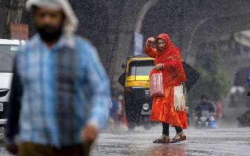 Thunderstorm Alert Latest News: A woman crosses a road amid rains in Jammu, Wednesday, April 17, 2019.
