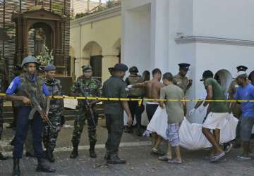 In this Sunday, April 21, 2019, photo, Sri Lankans carry a dead body following a blast at the St. Anthony's Church in Colombo, Sri Lanka