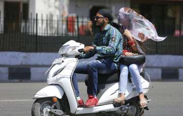 A woman pillion riding on a two wheeler covers her head with sari to protect from sun on a hot summer day in Jammu, India, Friday, May 31, 2019. Many parts of India are experiencing extreme heat conditions. (AP Photo/Channi Anand)