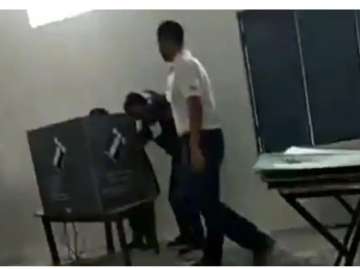 A screenshot from the video where the polling officer (in blue shirt) can be seen appearing to press a button. 