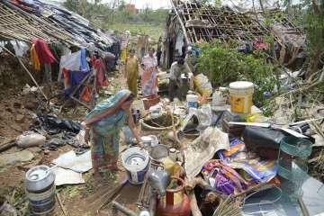 ?A woman sorts valuable items recovered from her damaged house due to Cyclone Fani, at a slum, in Bhubaneswar