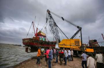 A crane lifts a boat from the shore to move it to a safer place ahead of the landfall of Cyclone Vayu, in Veraval, Wednesday, June 12, 2019.