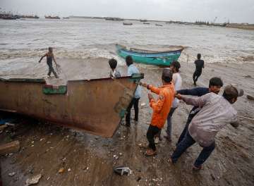 Fishermen move their boats to a safer place along the shore ahead of the landfall of Cyclone Vayu