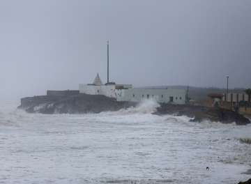 Huge wave hits the wall of a temple along the seashore during high tide