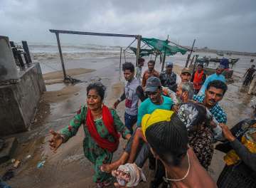 ?People carry an elderly man who was injured as strong winds and waves hit the shoreline ahead of the expected landfall of Cyclone Vayu