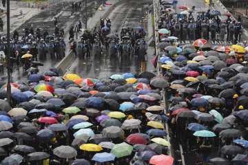 Protesters holding umbrellas face off police officers in anti-riot gear in Hong Kong on Monday, July