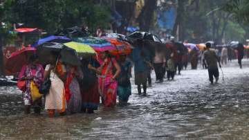 Pedestrians wade through a waterlogged street during monsoon rain.