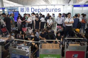 Airport security personnel stand guard as travelers walk past protesters holding a sit-in rally at t