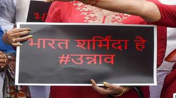 A protestor holds a card showing India is ashamed of what happened with the Unnao rape survivour.