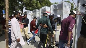 Pakistani police officers search spectators outside the National stadium in Karachi (AP)