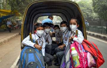 Students, wearing masks to get protection from air-pollution, go to their school by a rickshaw, in New Delhi, Friday, Nov. 1, 2019. 
