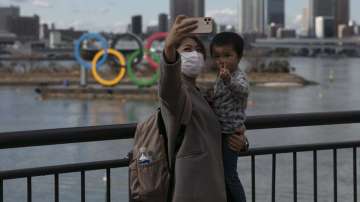  In this Wednesday, Jan. 29, 2020, file photo, a woman with a young boy takes a selfie with the Olympic rings, in Tokyo's Odaiba district. Tokyo Olympic organizers are trying to shoot down rumors that this summer's games might be cancelled or postponed because of the spread of a new virus