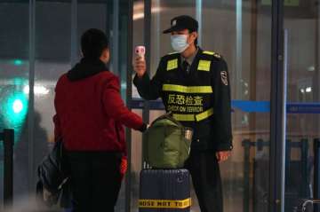 An airport staff member uses a temperature gun to check people leaving Wuhan Tianhe International Airport in Wuhan, China, Tuesday, Jan. 21, 2020. Heightened precautions were being taken in China and elsewhere Tuesday as governments strove to control the outbreak of a novel coronavirus that threatens to grow during the Lunar New Year travel rush. (AP Photo/Dake Kang)