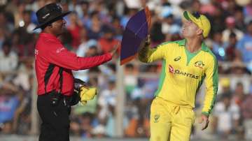 Australia's David Warner, right, holds a kite that fell on the ground during the first one-day international cricket match between India and Australia in Mumbai