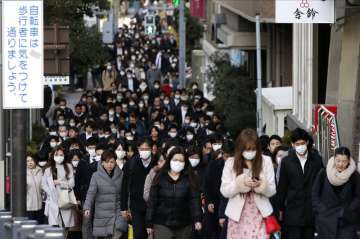 In this Feb. 20, 2020, file photo, people wear masks as they commute during the morning rush hour in