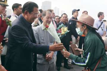 Cambodia's Prime Minister Hun Sen, left, gives a bouquet of flowers to a passenger who disembarked f