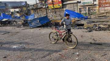 A boy walks past a neighbourhood vandalised by rioters during clashes between those against and those supporting the Citizenship (Amendment) Act in northeast Delhi