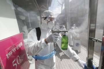 A worker wearing protective gears sprays disinfectant as a precaution against the coronavirus at a s