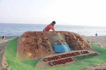 Sand artist Manas Sahoo makes a sand sculpture to create awareness against coronavirus, at Puri, Odisha, Thursday