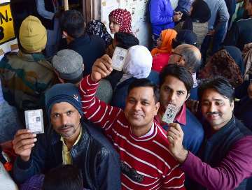 Voters show their identity cards as they wait in queues at the Abul Kalam Azad school polling station in Shaheen Bagh area, which has been witnessing a peaceful protest against the Citizenship Act for several weeks, during the Delhi Assembly elections, in New Delhi, Saturday
?
?