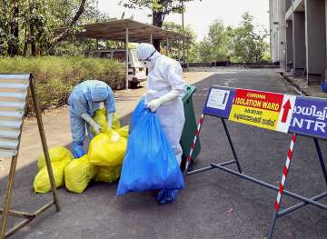 Medical staff dispose garbage outside an isolation ward for coronavirus, at a hospital in Kochi, on Monday