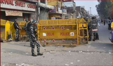Security personnel stand guard on the Chand Bagh - Bhajan Pura road in northeast Delhi, Tuesday, Feb