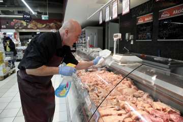 An employee disinfects the glass cover of a butcher counter to prevent the spread of the novel coron