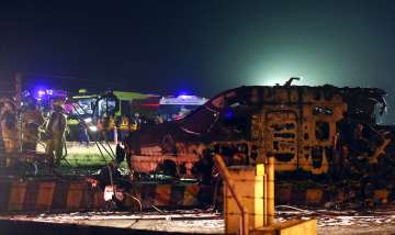 Firemen and rescuers talk beside the remains of a Lion Air, West Wind 24 aircraft after it caught fi