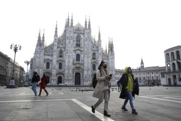 A woman wearing a mask walks past the Duomo gothic cathedral in Milan, Italy, on Sunday.
