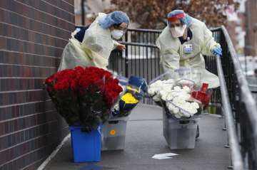 Emergency room nurses transport buckets of donated flowers up a ramp outside Elmhurst Hospital Cente