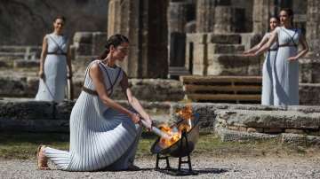 Greek actress Xanthi Georgiou, playing the role of the High Priestess, lights up the torch during the flame lighting ceremony at the closed Ancient Olympia site, birthplace of the ancient Olympics in southern Greece, Thursday, March 12